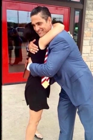 Sam R. Cammack III embracing a client outside a building.